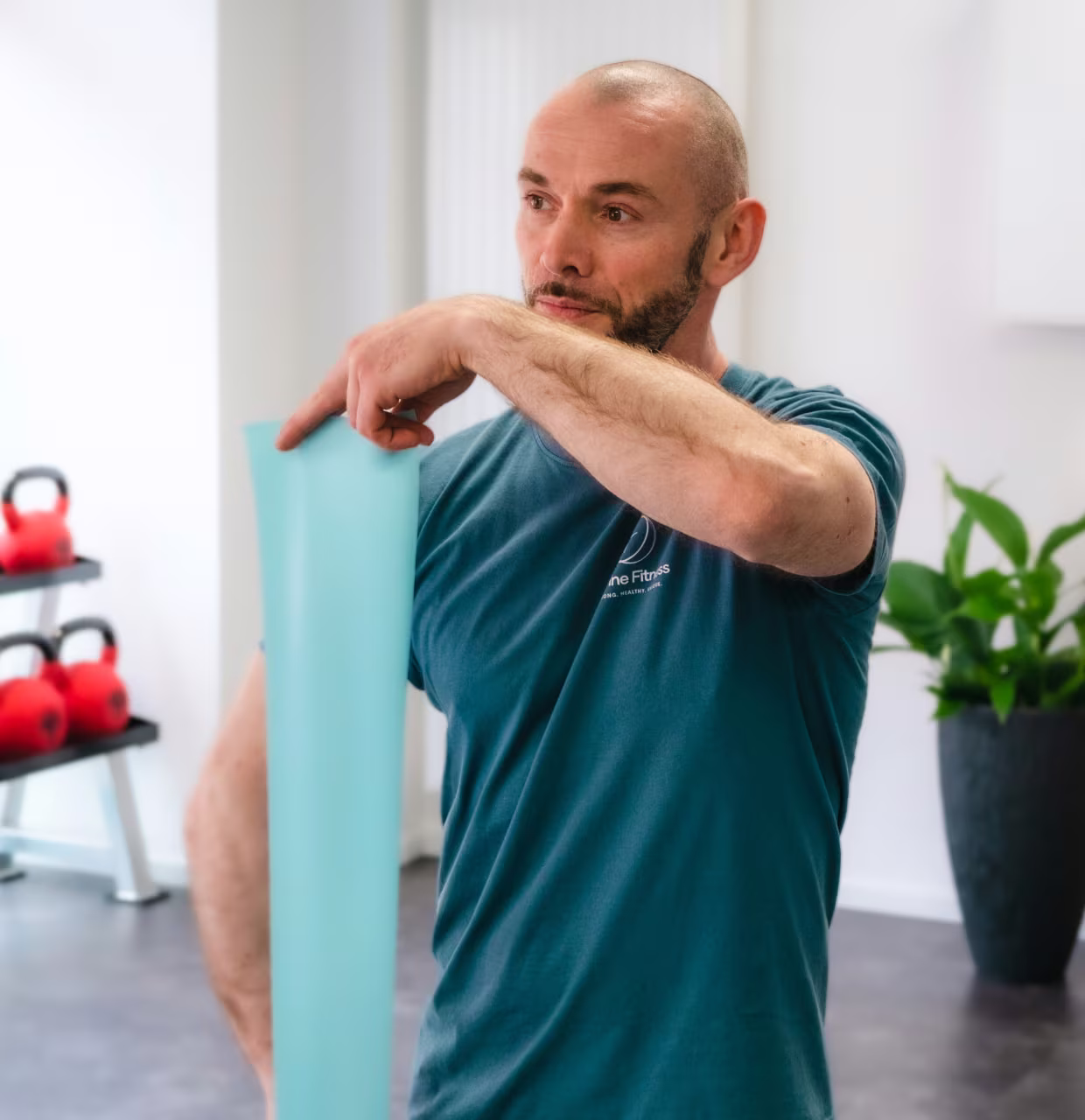 Florian Yesim spannt ein hellgrünes Widerstandsband in der Trainingsfläche von Define Fitness in Düsseldorf-Flingern